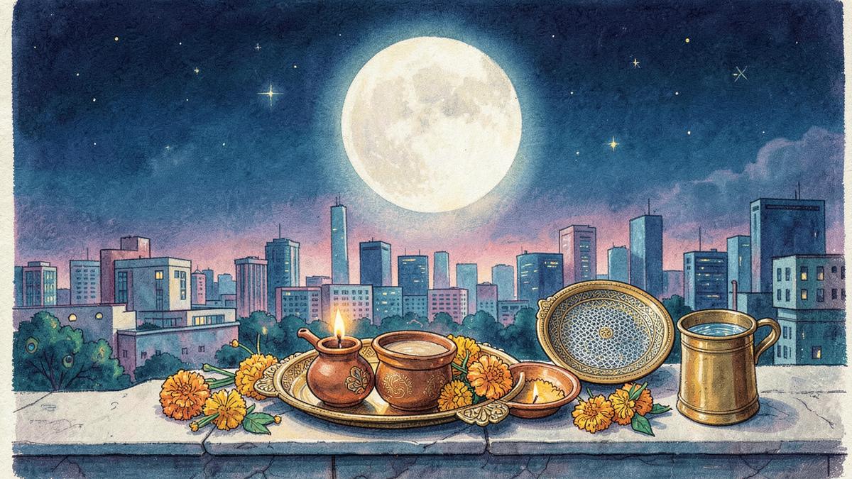 The moon rising over a city skyline, with a clay karwa, a lit diya, a puja thali, a sieve and a brass lota on a terrace ledge
